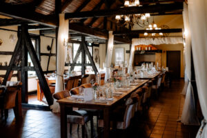 Großer Raum in der Moormühle mit langen Tafeln, Fachwerk und romantischem Licht.