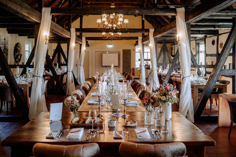 Großer Festsaal der Moormühle mit Fachwerk, gedeckten Tischen und Blumenarrangements