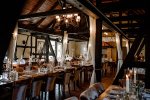 Blick in den rustikalen Hochzeitsfestsaal der Moormühle mit Holzbalken und romantischer Beleuchtung
