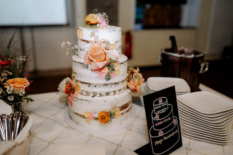 Dreistöckige Hochzeitstorte mit Blumendekoration und Desserttisch in der Moormühle