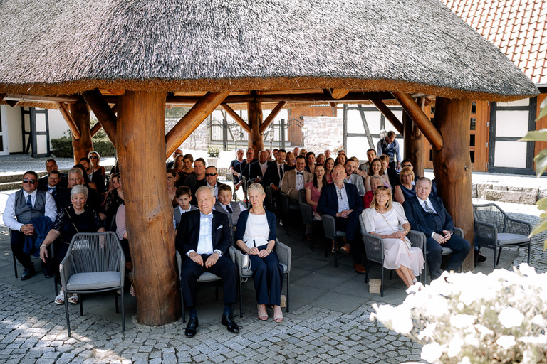 Hochzeitsgäste unter einem Reetdach-Pavillon im Innenhof der Moormühle in Burgdorf