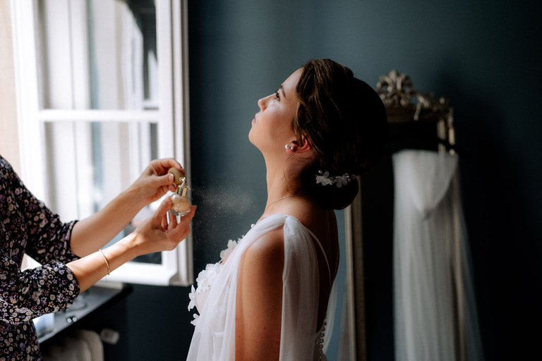 Braut trägt Parfüm auf, während sie sich auf Schloss Eldingen vorbereitet.