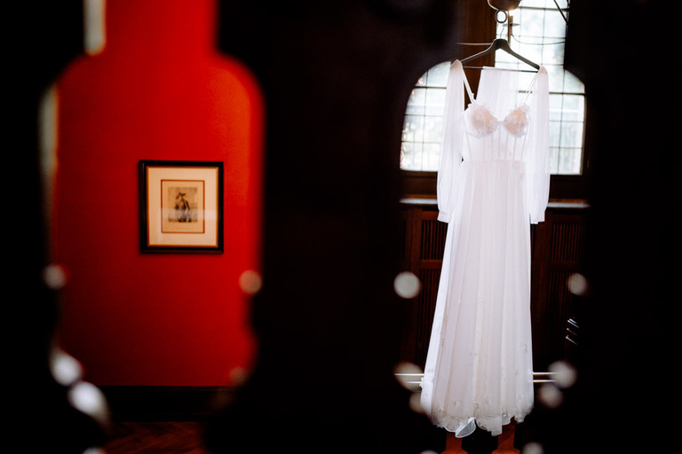 Weißes Brautkleid an einem Kleiderbügel vor einem Fenster in Schloss Eldingen.