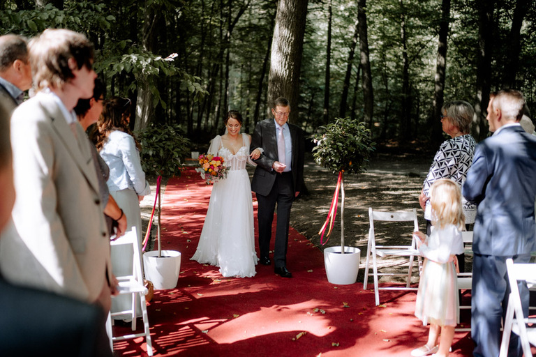 Die Braut und ihr Onkel schreiten den roten Teppich entlang zur freien Trauung.