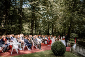 Gäste sitzen im Waldgarten von Schloss Eldingen während der Hochzeitstrauung.