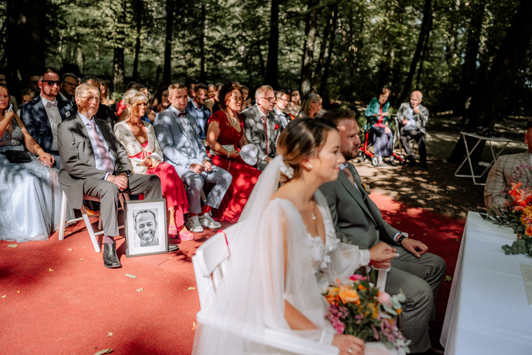 Die Gäste sitzen auf weißen Stühlen und verfolgen die Zeremonie im Grünen.