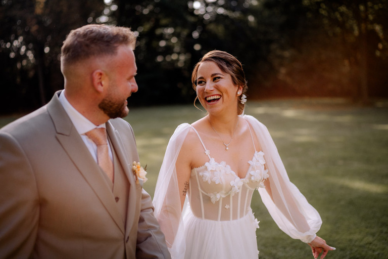 Das Brautpaar lächelt sich im Garten von Schloss Eldingen an.