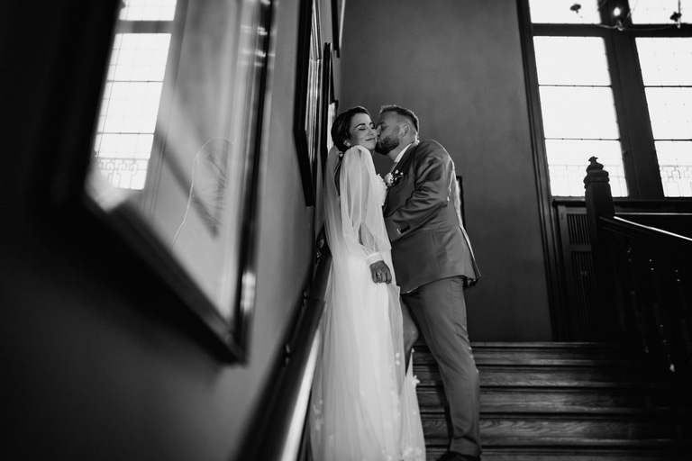 Das Brautpaar posiert in einem Schwarz-Weiß-Portrait auf der Treppe des Schlosses.