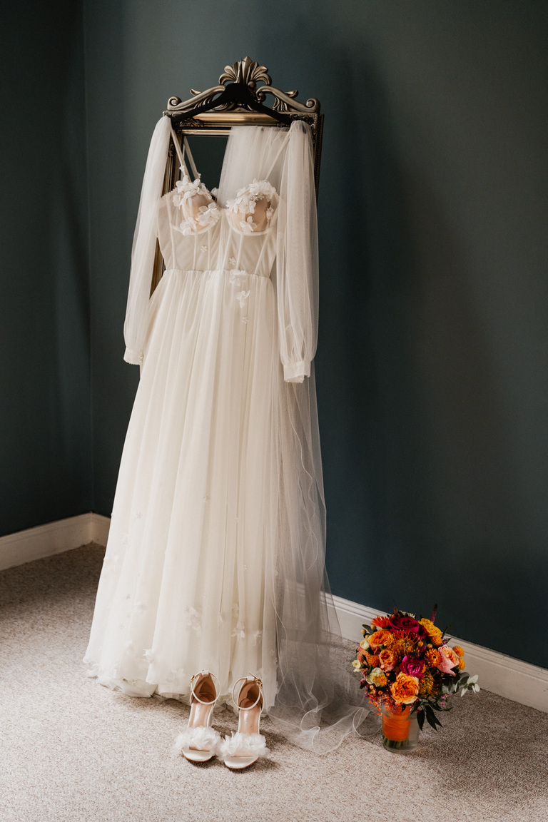 Elegantes Brautkleid mit floralen Details und Brautstrauß in lebendigen Farben auf Schloss Eldingen