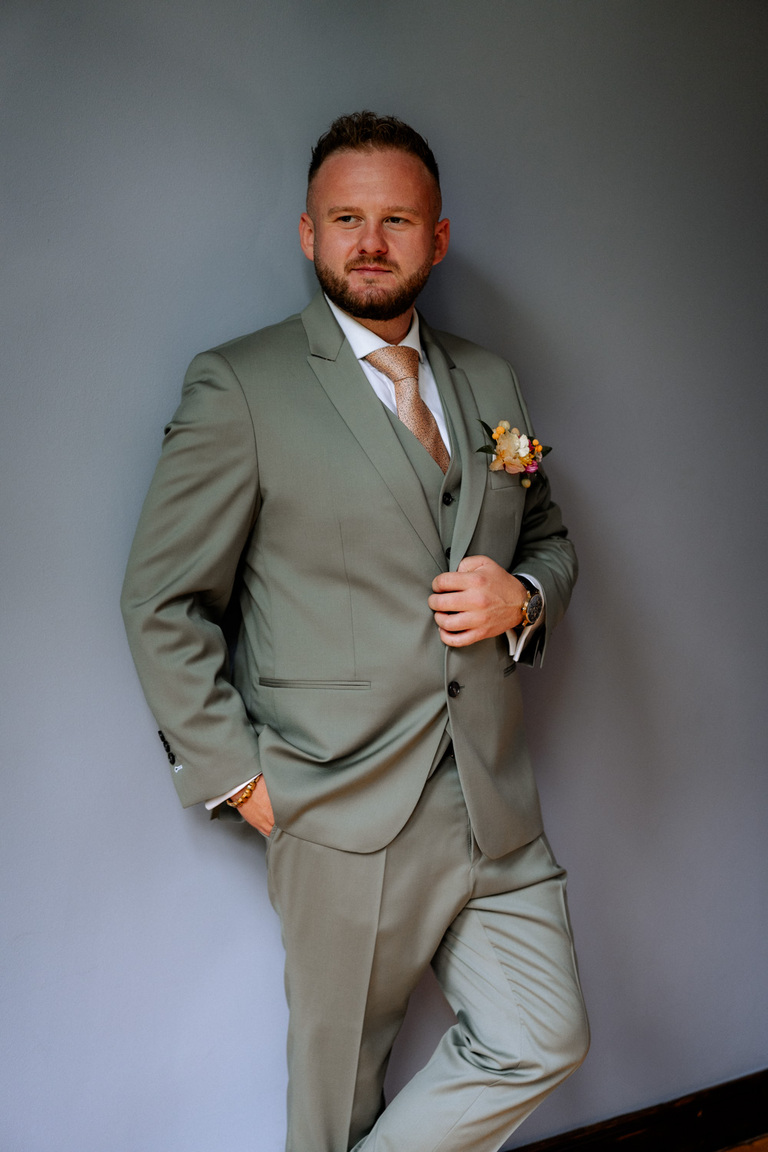 Der Bräutigam posiert in seinem eleganten Anzug vor der Kulisse von Schloss Eldingen.