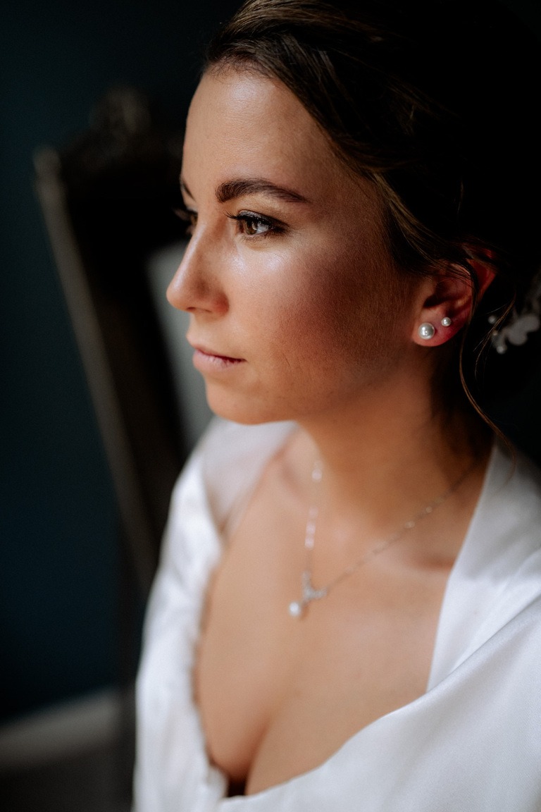 Die Braut im natürlichen Licht mit Fokus auf ihr elegantes Make-up und Schmuck.