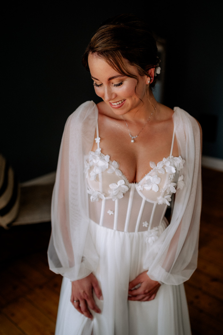 Die Braut in ihrem Hochzeitskleid mit zarten Blumenapplikationen auf Schloss Eldingen.