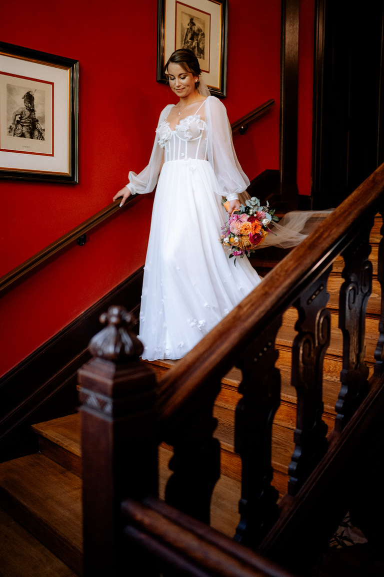 Die Braut schreitet die Treppe von Schloss Eldingen hinunter, bereit für die Trauung.