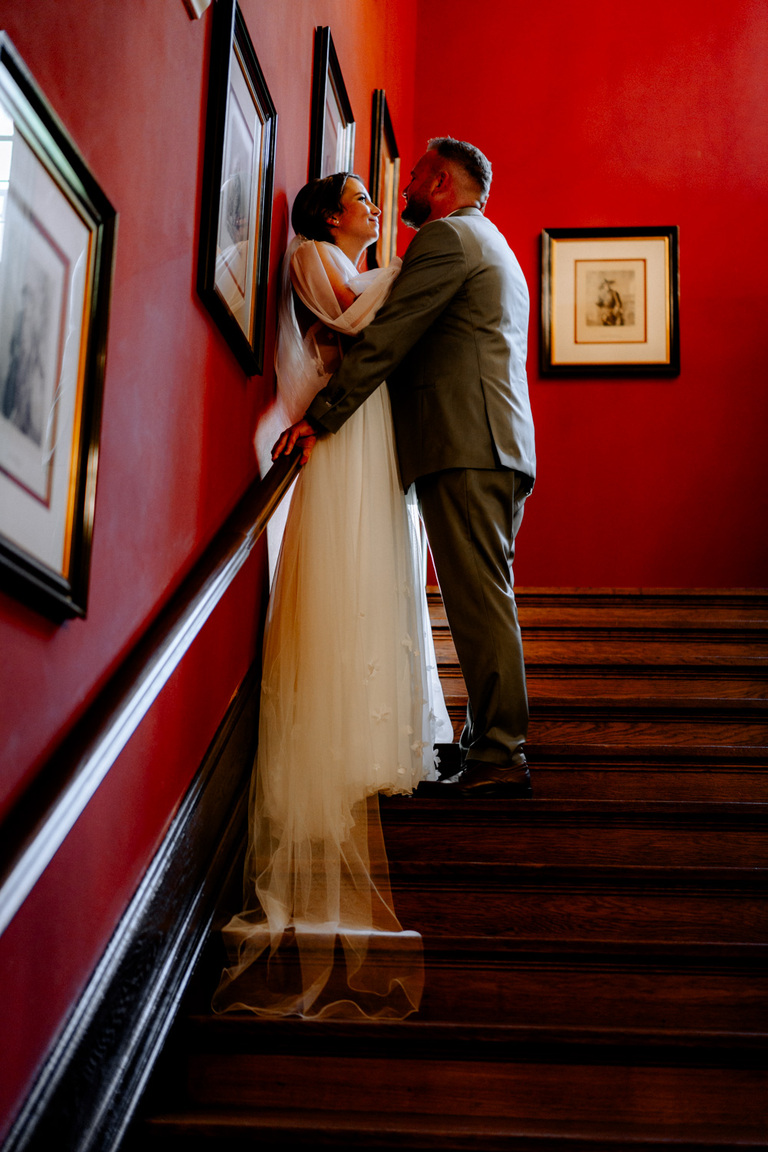 Bräutigam und Braut in eleganter Pose auf der prachtvollen Treppe des Schlosses