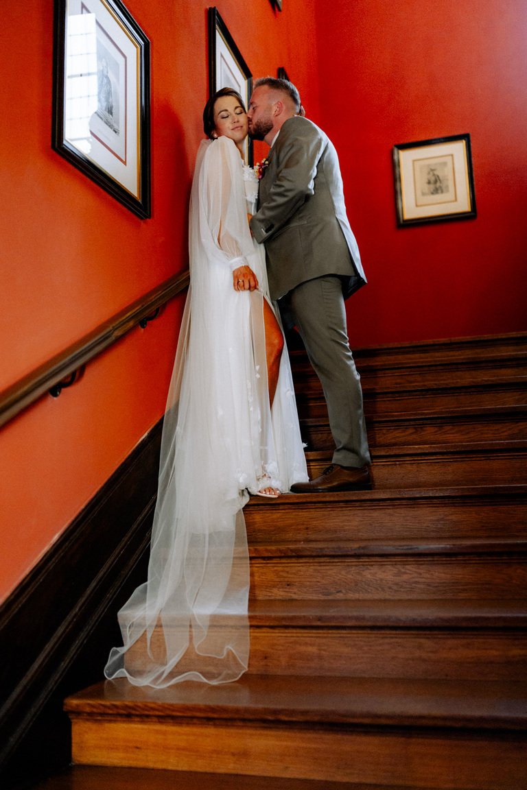Bräutigam und Braut in eleganter Pose auf der prachtvollen Treppe des Schlosses