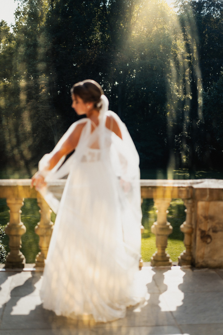 Braut mit wehendem Schleier im goldenen Licht auf einem Balkon