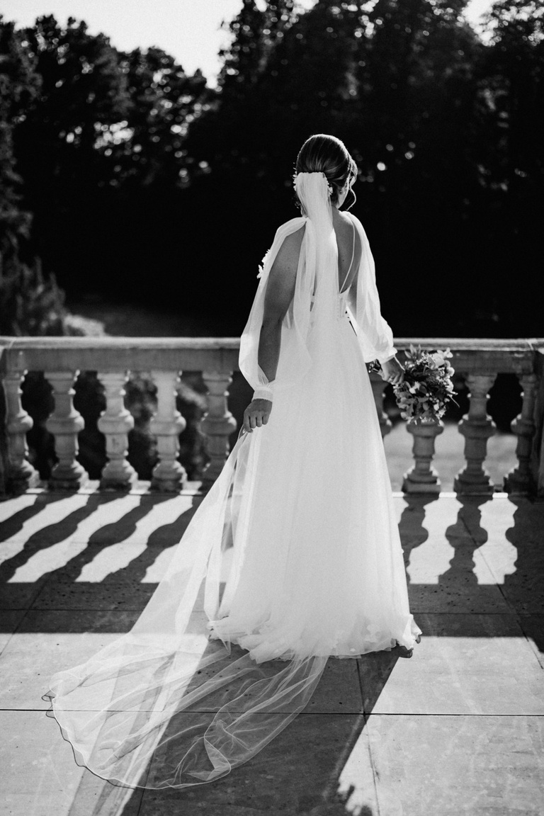 Rückenansicht einer Braut mit fließendem Schleier auf dem Balkon von Schloss Eldingen.