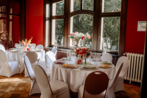 Hochzeitstische mit eleganter Blumendekoration im roten Saal von Schloss Eldingen.