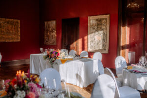 Hochzeitstafel vor einem Wandteppich und mit Blumenarrangements im Schloss Eldingen.