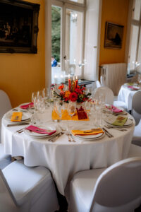 Festlich gedeckter Hochzeitstisch mit orangefarbenen und pinken Details im Schloss Eldingen.